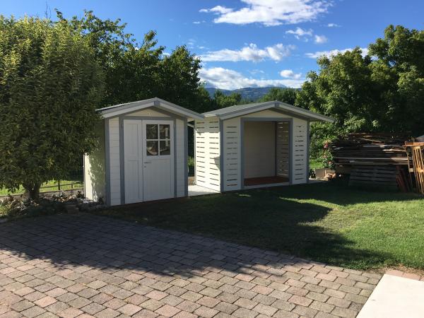 FOTO 14 casetta a pareti colorata cm 200x200 con aggiunta di : laccatura bianca, bordi grigio scuro, porta doppia cm 120, finestra fissa sulla porta, scuretti sulla finestra, fioriera, grondaie, a dx casetta legnaia cm 300x200.